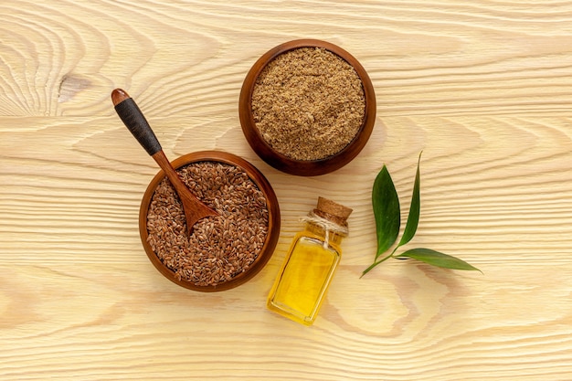 Flaxseeds in a spoon and bowl with a bottle of flaxseed oil and flaxseed flour