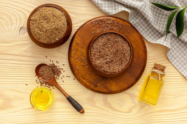 Flaxseeds in a spoon and bowl with a bottle of flaxseed oil and flaxseed flour