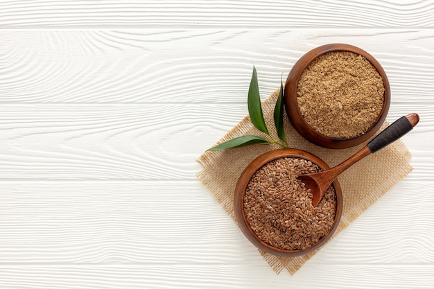 Flaxseeds in a spoon and bowl with a bottle of flaxseed oil and flaxseed flour