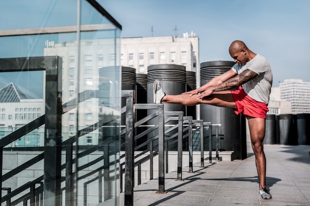 Flexibility exercise. Handsome serious sportsman trying to touch his toes whilw doing a flexibility exercise