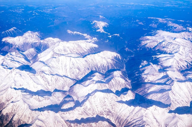 Flight above Mountains peaks covered by snow