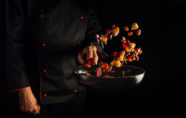 Flight of vegetables over the frying pan in the hands of the chef