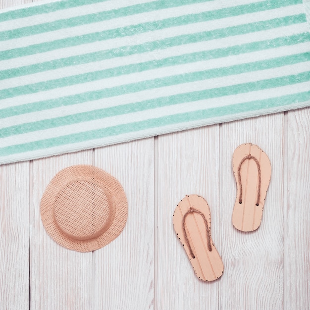 flip-flops, cotton towel with blue stripes, hat from sun on white wood