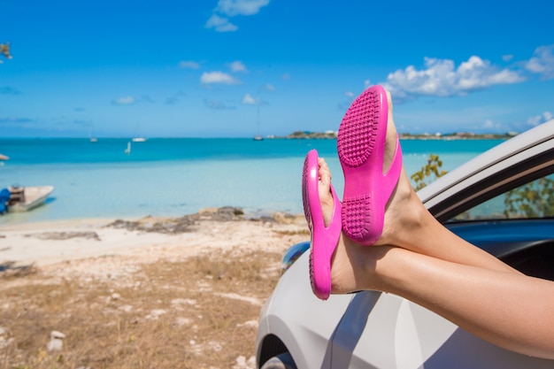 Flip Flops from the window of a car on background tropical beach