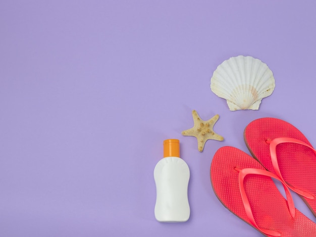 Flip flops sunscreen and shell and starfish on very peri background