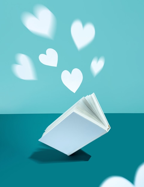 Floating Cute paper heart and white cover book on bold color blue-aquamarine-turquoise background. Modern photo. Concept National Book Lovers Day. happy holydays.Romantic, love storytelling.copy space