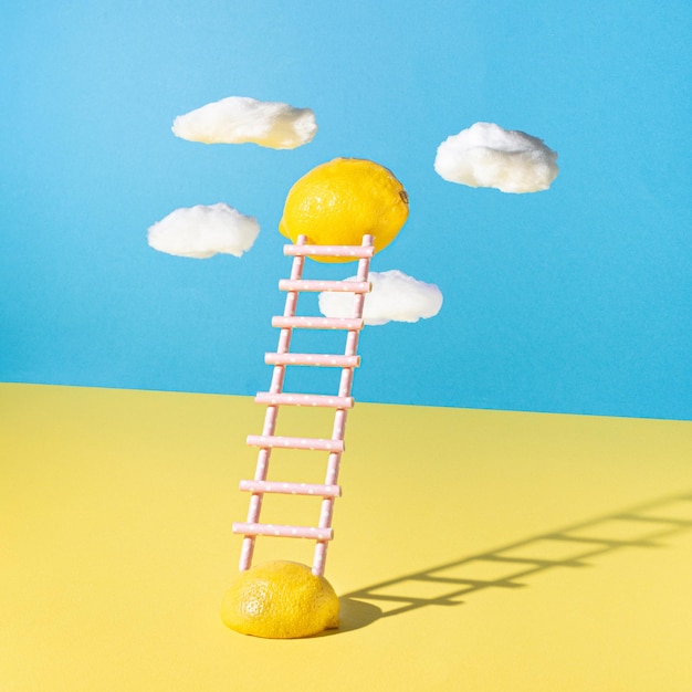 Floating lemons with ladders made of juice straw against yellow