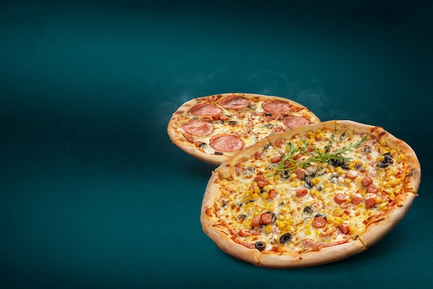 Floating, smoking italian pizzas on a turquoise background with diferent toppings. Fresh baked pizza with copy space for text or design