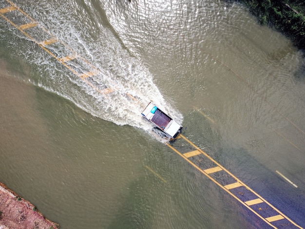 Photo flooded roads, people with cars running through. aerial drone photography shows streets flooding and people's cars passing by, splashing water.