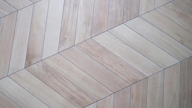 Floor lined with herringbone wooden laminate or parquet background closeup