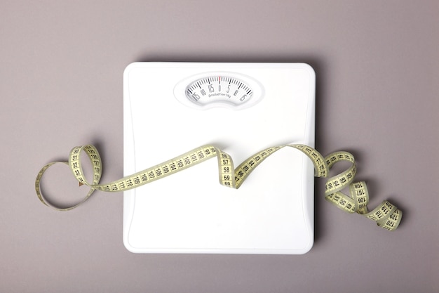 Floor scales and tape measure on a colored background top view