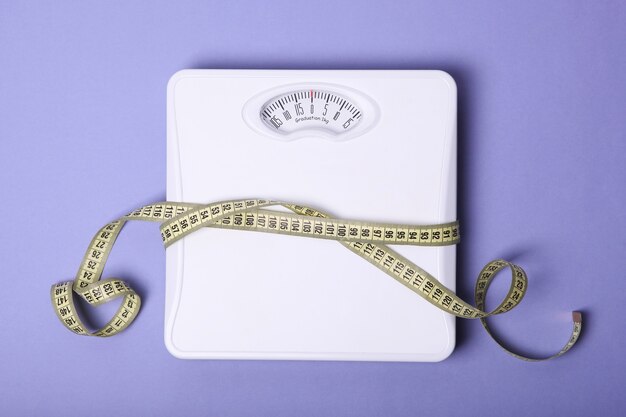 Photo floor scales and tape measure on a colored background top view