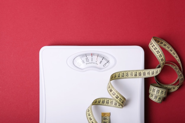 Floor scales and tape measure on a colored background top view