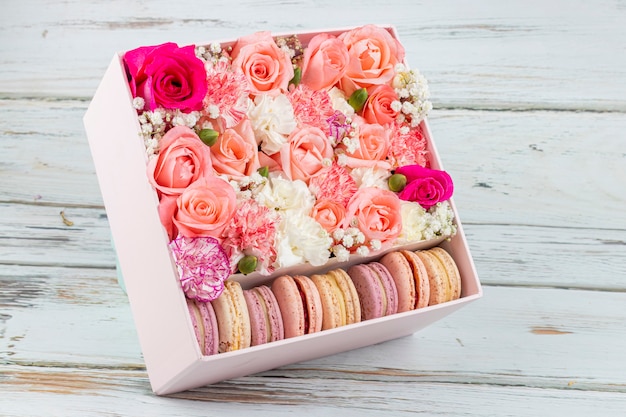 Floral arrangement of pink roses with macarons of different colors