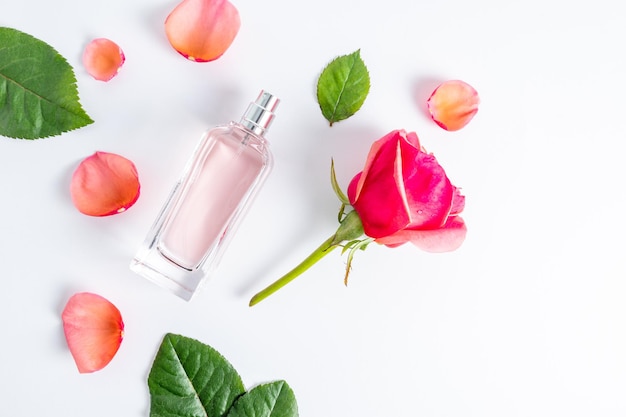 Floral arrangement with an elegant bottle of women's perfumes and rose petals flower bud flat lay top view white background aroma presentation