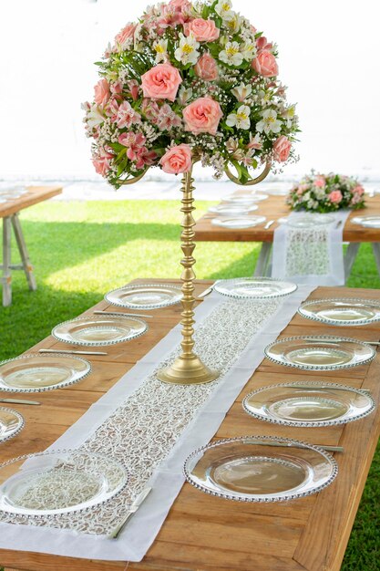 Floral arrangement on a wooden table with glassware set up in a garden for a social event in Mexico