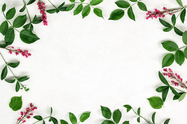 Floral pattern made of green leaves branches on textured light background Flat lay top view