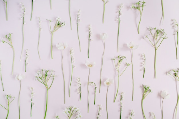 Floral pattern made of lily of the valley, green leaves, branches on pink