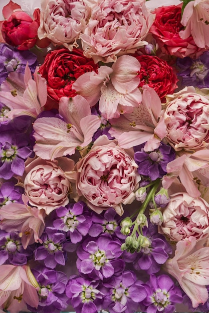 Floral pattern made of pink and red roses flowers and purple wildflowers Flat lay top view Valentine's background Floral texture Pattern of flowers