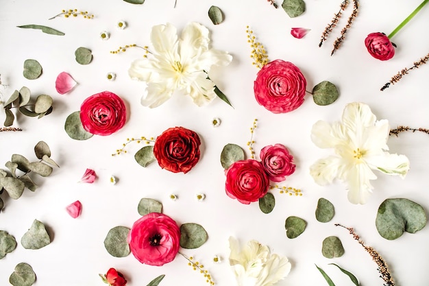 Floral texture with pink and red roses or ranunculus, white tulips and green leaves