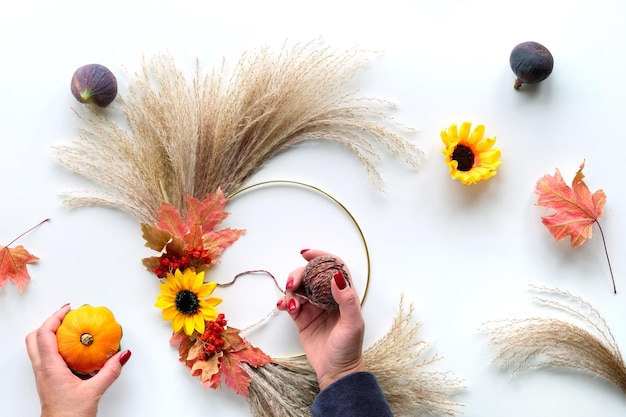 Floral wreath from dry pampas grass and Autumn leaves Hands tie decorations to metal frame