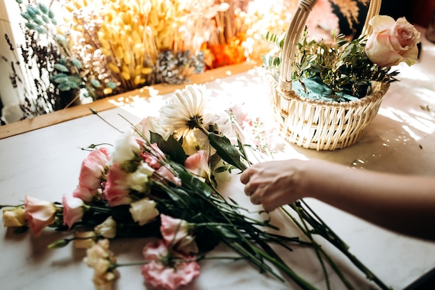 Florist collections a bouquet in the basket from fresh chamomile and eustoma in the flower shop .