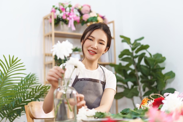 Florist concept Female florist arrange white chrysanthemum in vase with happiness in flower shop