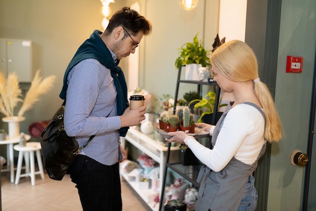 A florist in a flower and live plant shop advises a customer on potted plants