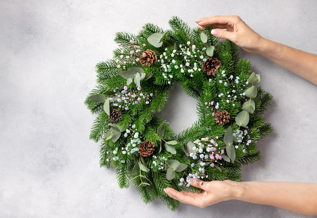 Photo florist hands holding christmas wreath christmas wreath workshop