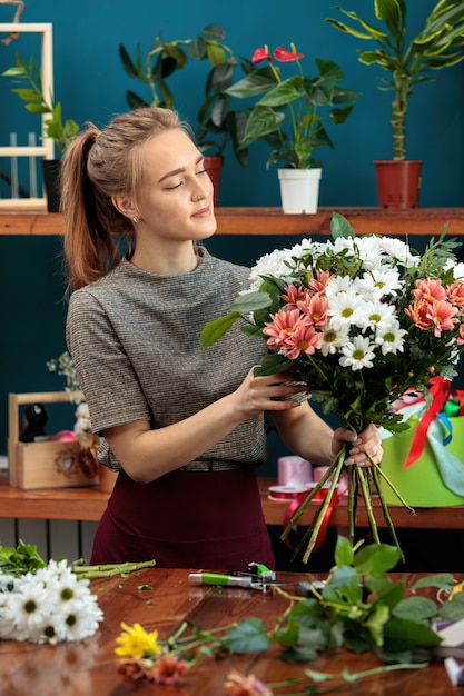 Florist makes a bouquet of multi-colored chrysanthemums. A young adult girl works with enthusiasm.