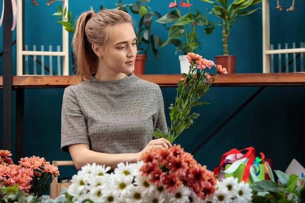 Florist makes a bouquet of multicolored chrysanthemums A young adult girl works with enthusiasm