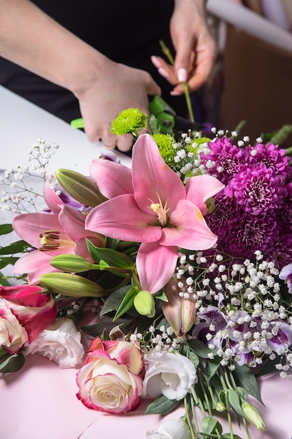 Florist's work in the process of creating a bouquet with lilies in the workplace