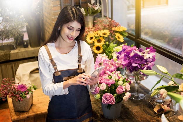 florist standing at her flower shop and using her telephone to take orders 