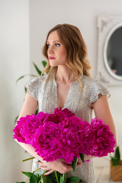 florist woman creating bouquets of flowers in workshop Entrepreneur is holding bouquet of peonies