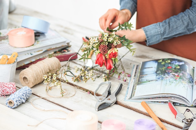 Florist at work: the female hands of woman making fashion modern bouquet of different flowers