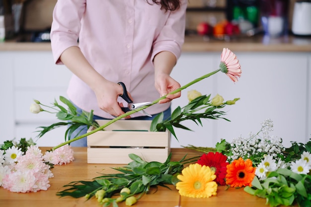 Florist at work pretty young brunette woman making fashion modern composition of different flowers at home