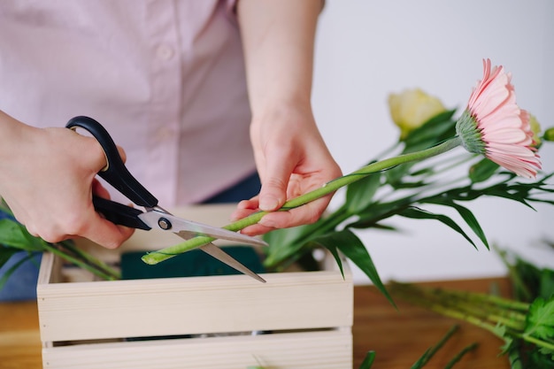 Florist at work young brunette woman hands making fashion modern composition of different flowers at home