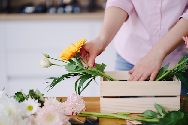 Florist at work young brunette woman hands making fashion modern composition of different flowers at home