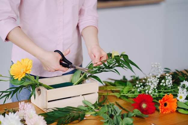 Florist at work young brunette woman hands making fashion modern composition of different flowers at home