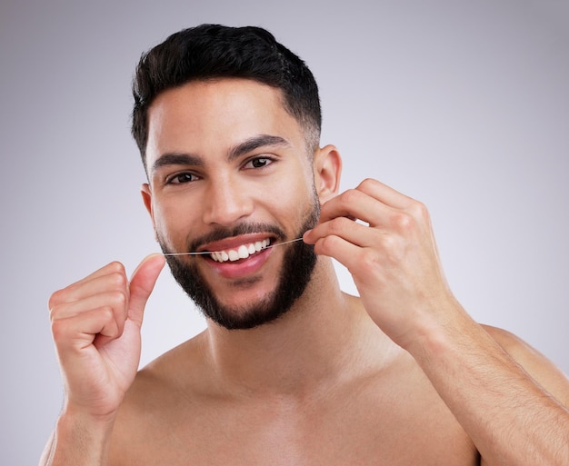 Floss daily for fresh breath Shot of a young man flossing his teeth against a studio background