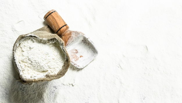 Flour in a bag with a wooden scoop.