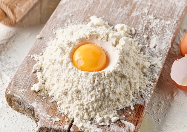 Flour and egg yolk on wooden kitchen cutting board