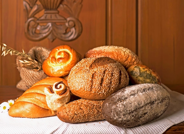 Flour products of various types Wicker basket with different types of bread and sweet buns on a wooden table