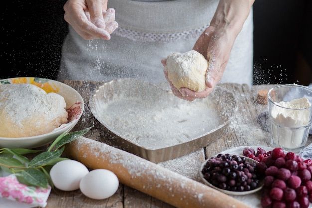 Flour scatters in the air. Work with the test. Cooking a pie at home.