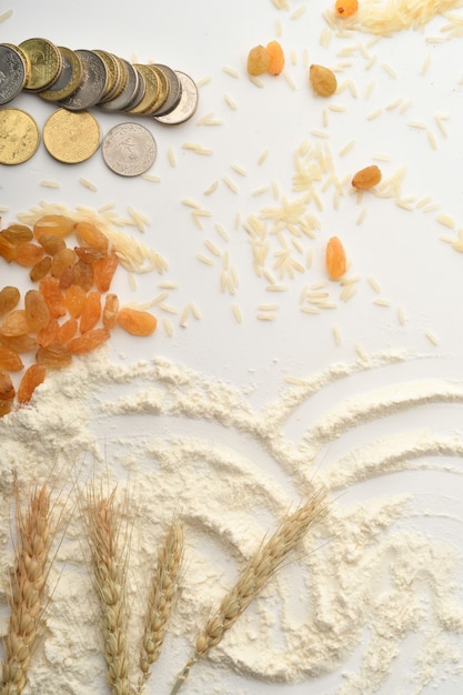 Flour, wheat, rice, raisins and coins on a white background