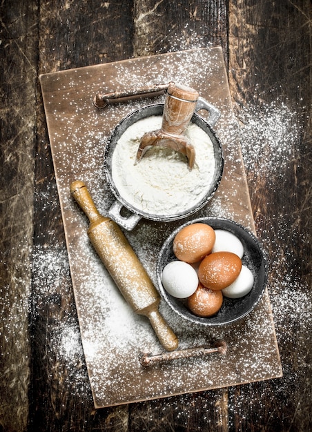 Flour with fresh eggs. On a wooden surface.