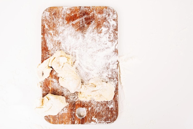 Floured cutting board with raw dough Top view on baker workplace with left pastry on it free space on white table Culinary bakery confectionery concept