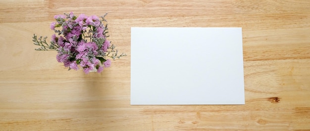 Flower bouquet and blank note paper on wood background banner with copy space top view flat lay