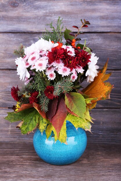 Flower bouquet in blue vase on grey wooden background