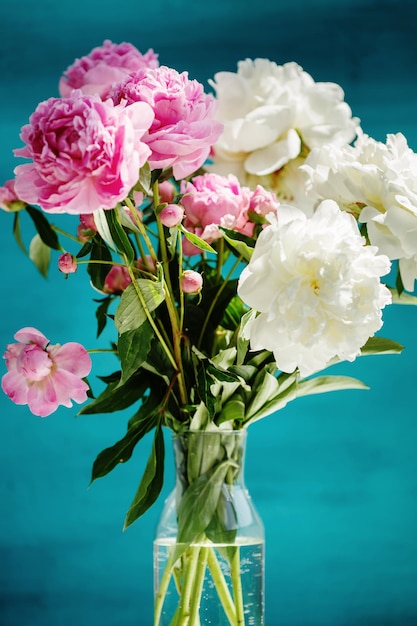 Flower bouquet of pink natural peonies flowers in a vase over turquoise background spring and summer season flowers